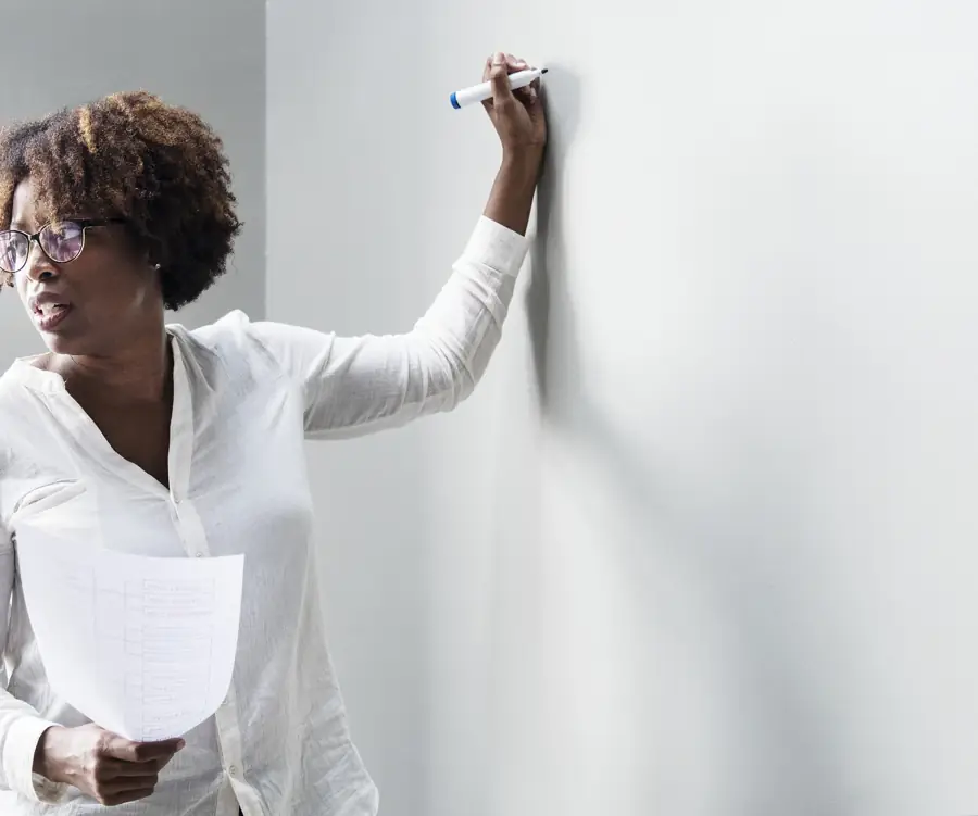 Bookkeeper writing figures on a whiteboard with notes in hand