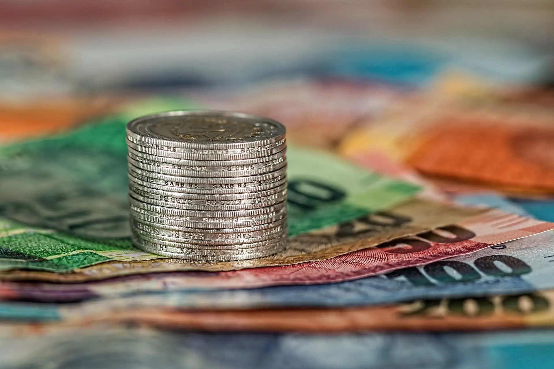 Stack of coins resting on bank notes